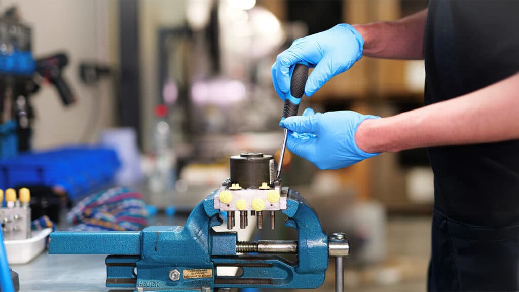 Technicien utilisant un outil sur un dispositif de montage en atelier.